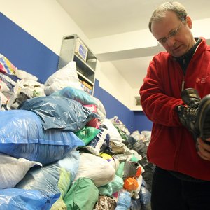 A volunteer checking the condition of a shoe in a homeless shelter.