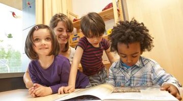 Kindergarten children read a book with thier teacher in the classroom.