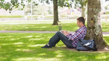 A college student working from his laptop outside.