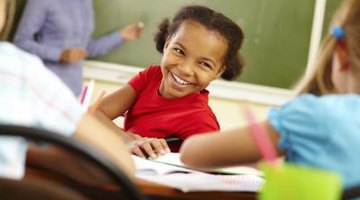 Young girl student talking to other girl students in the classroom.