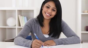 Student smiling while writing in notebook at home