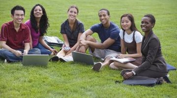 Smiling students studying together on campus lawn.