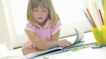 A young girl is flipping through a coloring book.