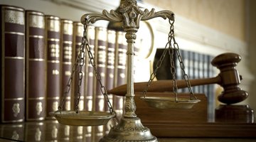 Justice scales, a gavel, and law books on a marble counter.