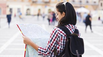 Student holding map up in foreign country