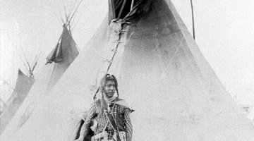 This Blackfoot Native American stands before a teepee.