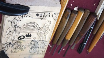 A carved woodblock and set of cutting tools.