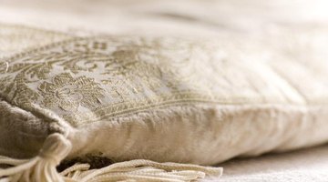 A white pillow resting on a white bed sheet.