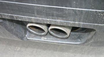 Low angle view of a male mechanic fixing an exhaust pipe on a car