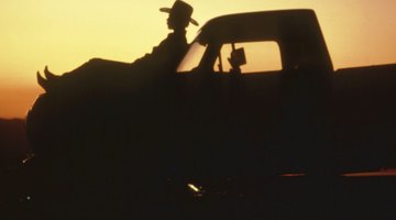 Silhouette of man reclining on hood of truck