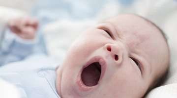Baby girl yawning in a white round crib