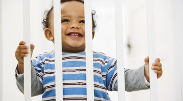 Toddler boy (18-21 months)  climbing out of crib, rear view