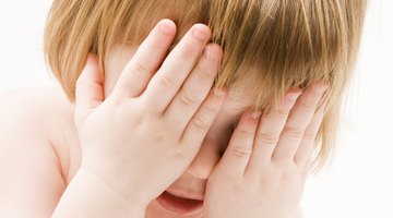 Pregnant woman holding crying girl while talking on telephone