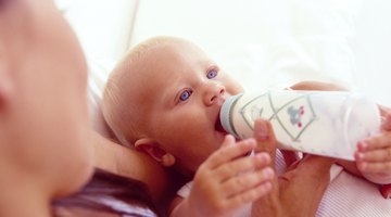 baby with small bottle in bed