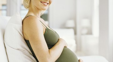 Attractive pregnant woman holding a bowl of salad while standing