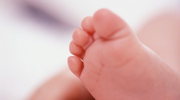 Close-up of a person's hands holding a baby's legs