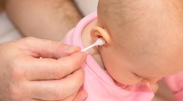 Mother cleaning mucus of baby with nasal aspirator