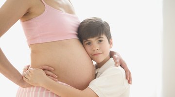 Daughter listening to pregnant mid adult mothers belly, smiling