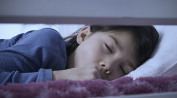 woman talking on the telephone and looking at thermometer while boy (10-12) sleeps in bed