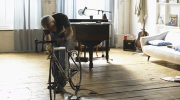 A man fixing his bike in a city loft apartment.