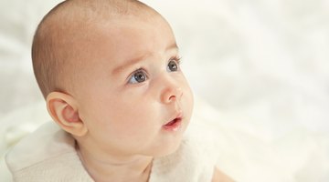 A caucasian older sister bottle feeds her little baby brother