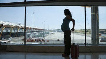 Pregnant woman pulling a suitcase inside airport