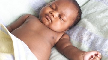 Baby (3-6 months) lying on white sheets, close-up