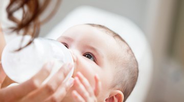Mother holding a baby and bottle with breast milk