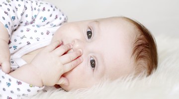 Newborn baby dressed in white laying on her back