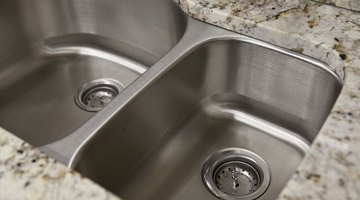 A close-up of two stainless steel sinks in a granite countertop.