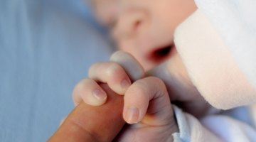 Close-up of a baby's hand holding an adult's hand on a laptop