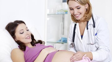 Pregnant woman holding headphones to stomach