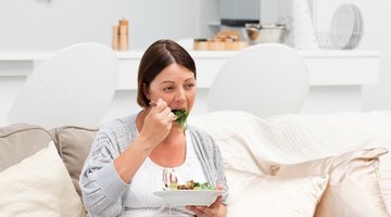 Pregnant female choosing between broccoli in glass bowl and vitamins