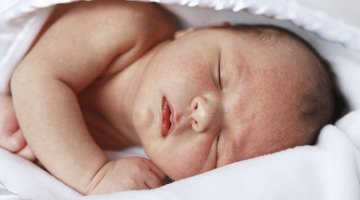 Newborn baby dressed in white laying on her back