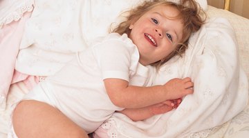 Child playing with blanket on bed