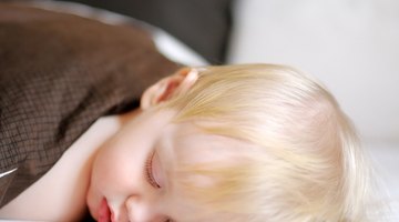 Child playing with blanket on bed