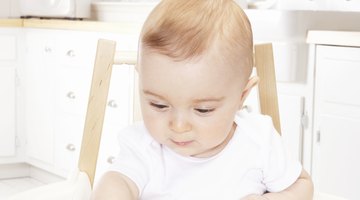 Baby girl (6-9 months) lying on bed, low section