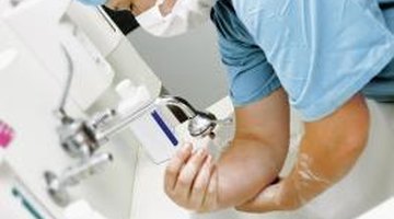 Already masked, a surgeon washes hands to prepare for surgery.