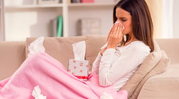 Woman blowing her nose on couch