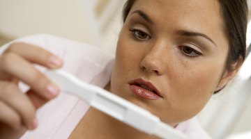 close-up of a young woman crossing her fingers while looking at a pregnancy test