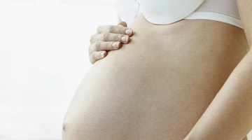 Attractive pregnant woman holding a bowl of salad while standing