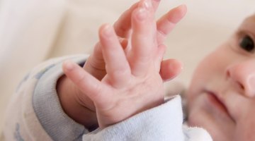 Close-up of a baby's hand holding an adult's hand on a laptop