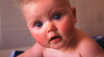 Female baby (6-9 months) crawling towards camera as another baby playing behind