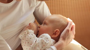 Mother Holding Newborn Baby Daughter At Kitchen Table