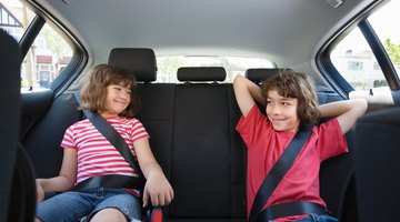 Three girls (6-8 years) sitting on rear seat of car during road trip