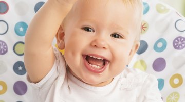 Mother Feeding Baby Sitting In High Chair At Mealtime