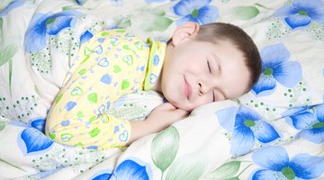 Adorable kid boy after sleeping in white bed with toy