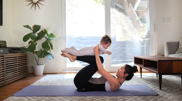 Woman doing downward dog yoga pose with her son in living room