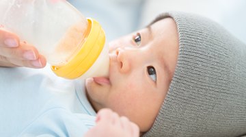 Mother Holding Newborn Baby Daughter At Kitchen Table