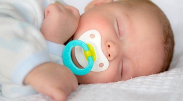 elevated close up view of a baby (6-12 months) sleeping with a dummy in its mouth